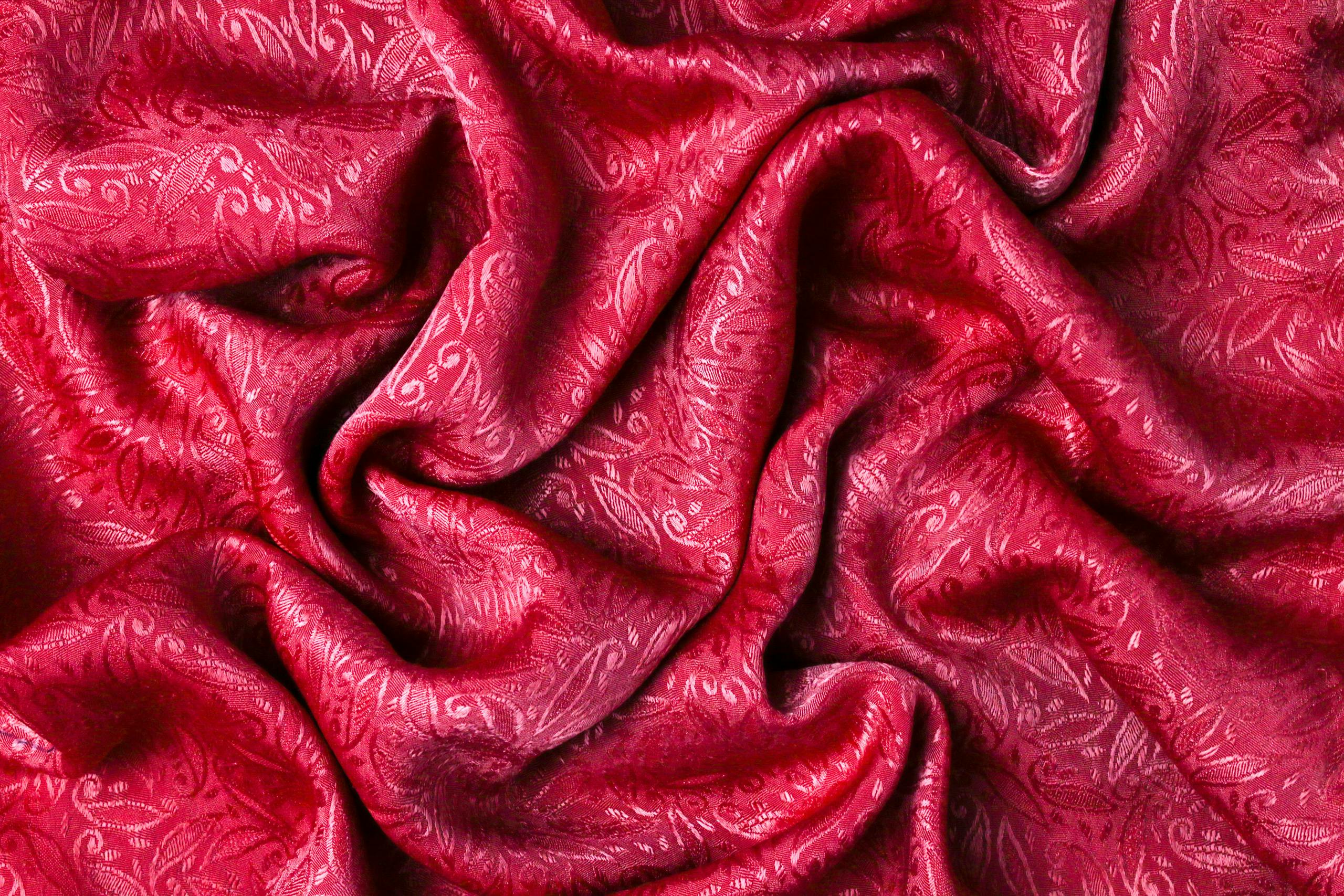 Vibrant close-up of red fabric with intricate patterns and soft folds.